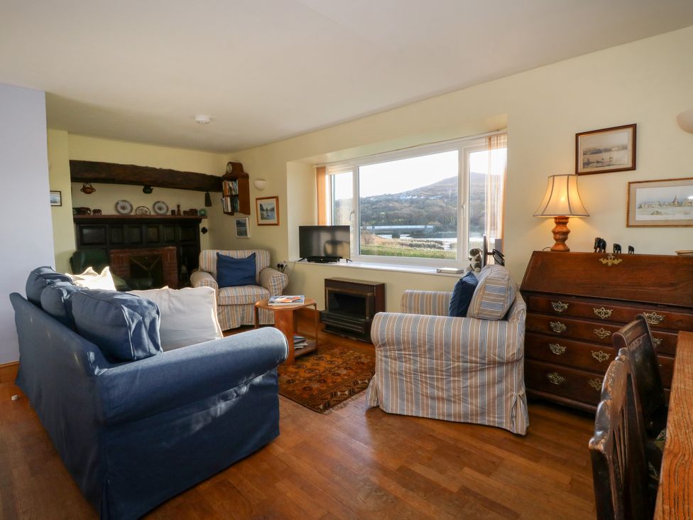 A living room with a sofa, armchair, television and decorative items at Bryncyn in Newport, Pembrokeshire