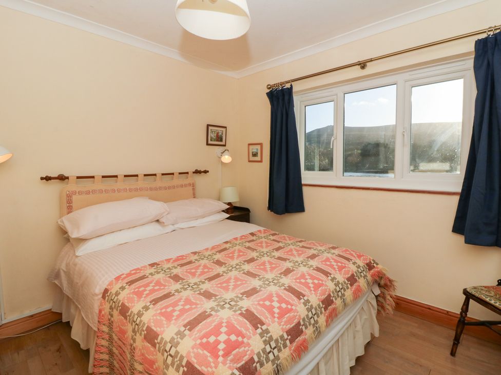 A bedroom featuring a bed with a patterned blanket at Bryncyn in Newport, Pembrokeshire