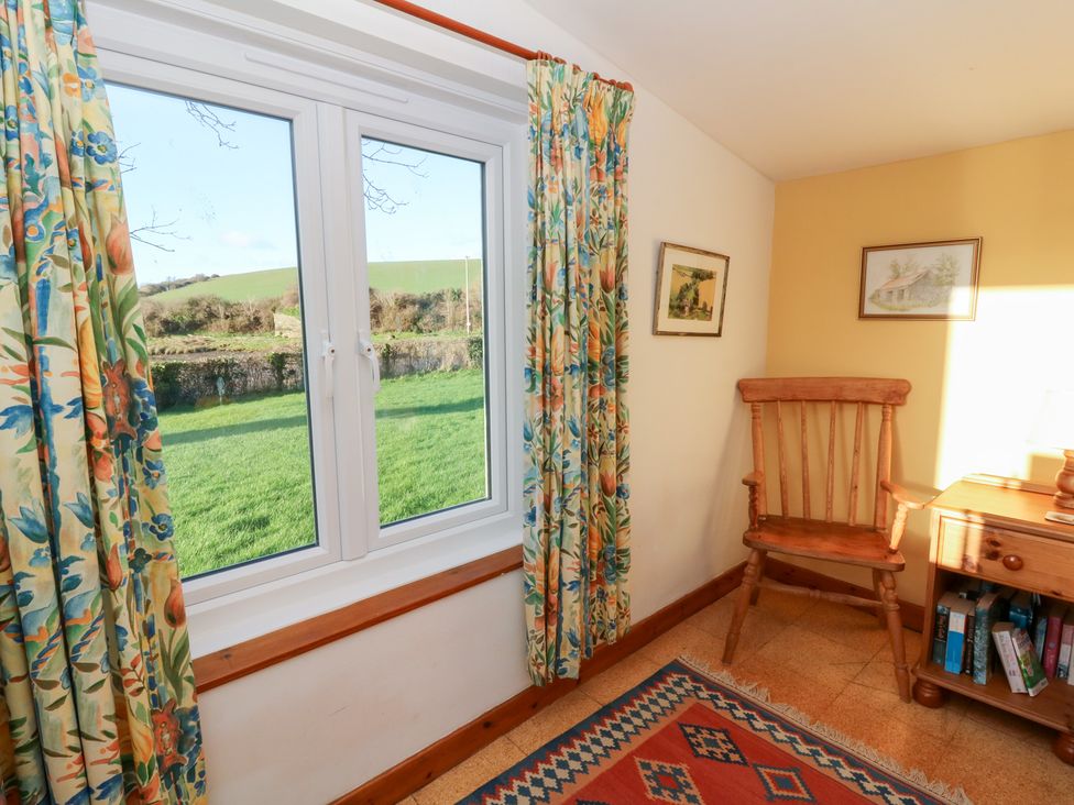 A room with a window, chair, and bookshelf at Bryncyn, Newport, Pembrokeshire