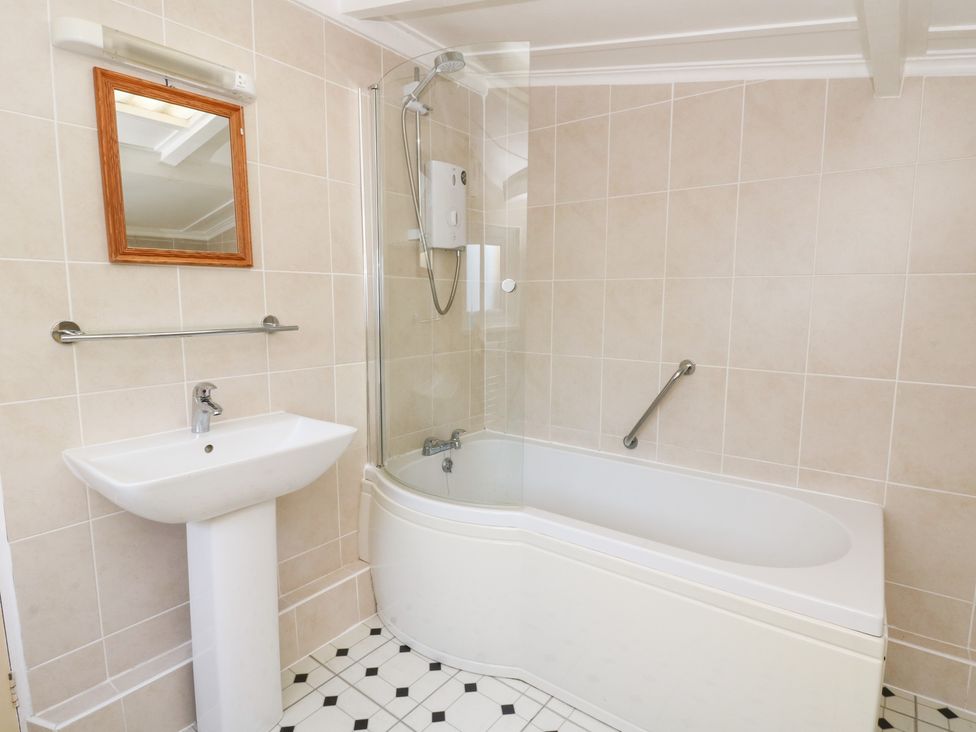 A bathroom with a bathtub, sink, and mirror at Bryncyn in Newport, Pembrokeshire