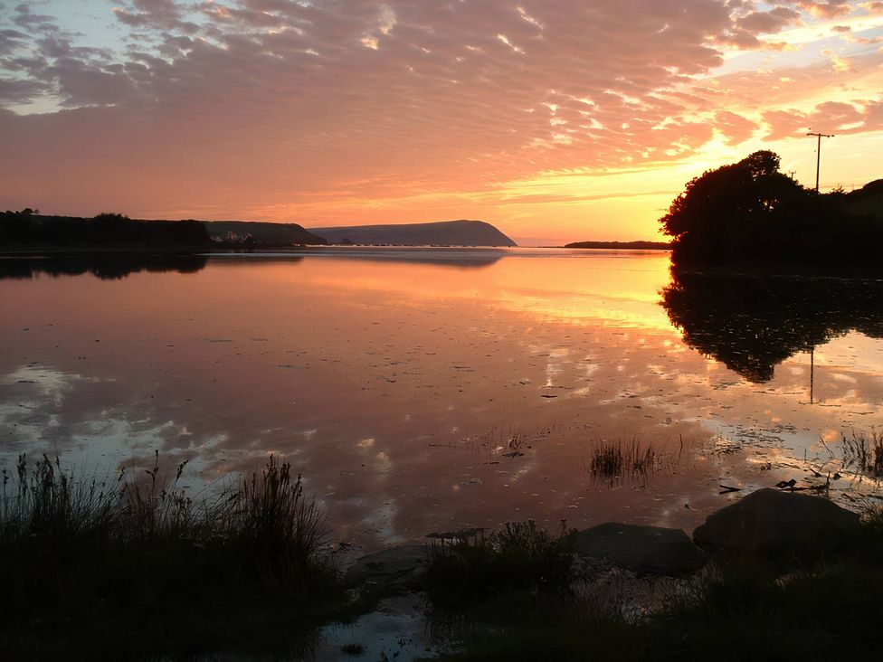 A sunset over a calm body of water at Bryncyn in Newport, Pembrokeshire