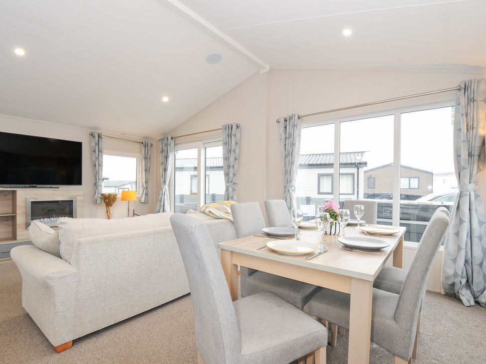 A living room with a dining area and a television at 2 Summerleaze in Bude