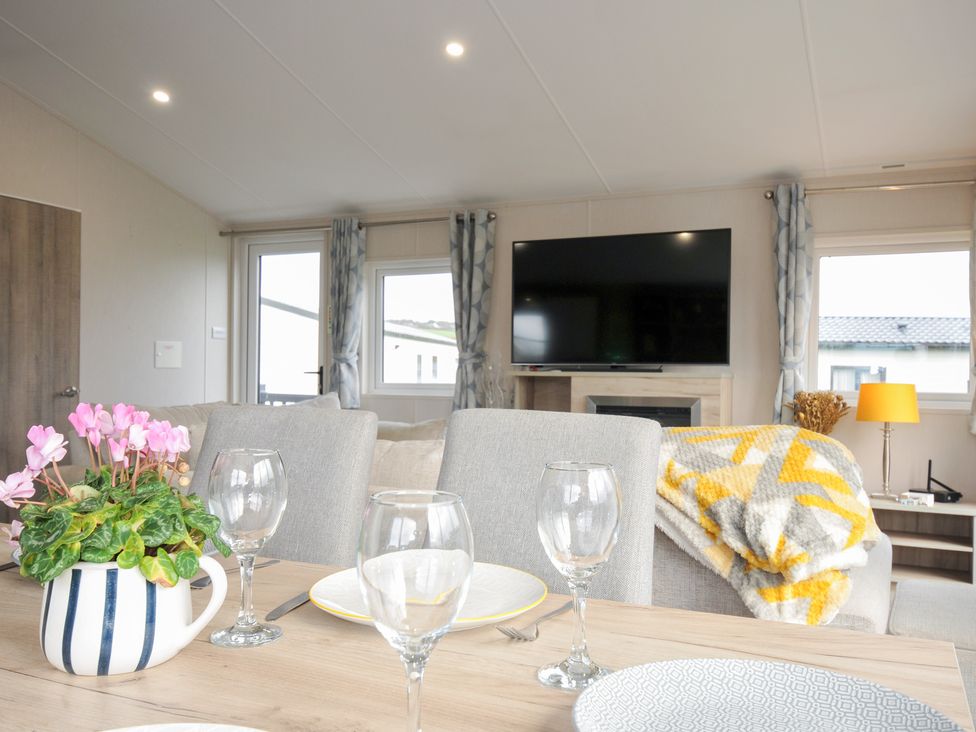 A living room with a table, chairs, and a television at 2 Summerleaze in Bude