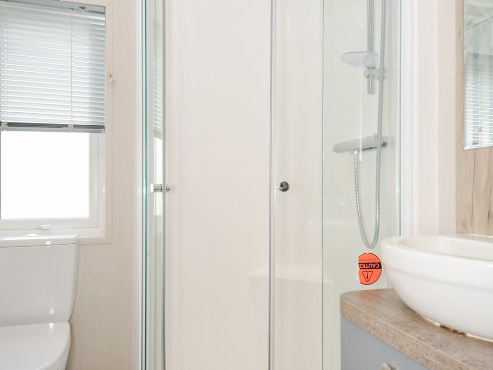 A bathroom featuring a toilet, shower enclosure, and sink at 2 Summerleaze in Bude