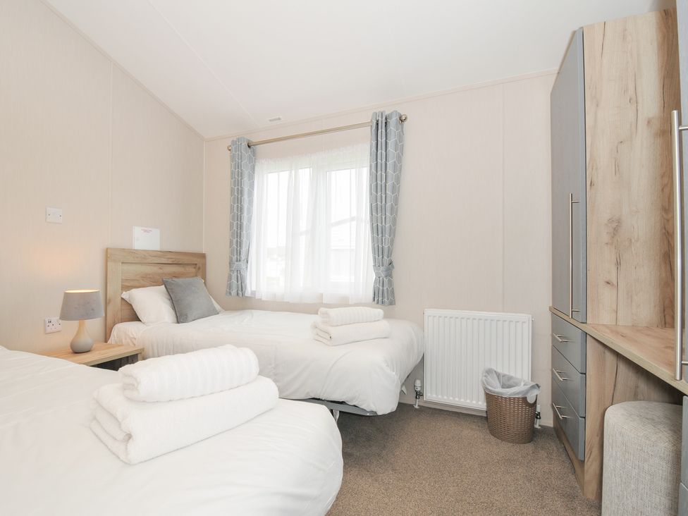 A bedroom with two beds and a wardrobe at 2 Summerleaze in Bude