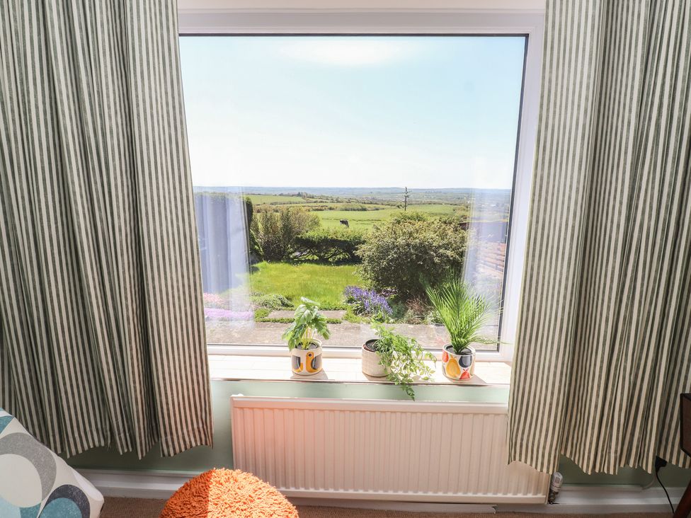 A living room with a window overlooking a green landscape at Mona View in Amlwch