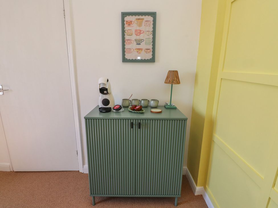 A cupboard with a coffee machine and cups at Mona View in Amlwch