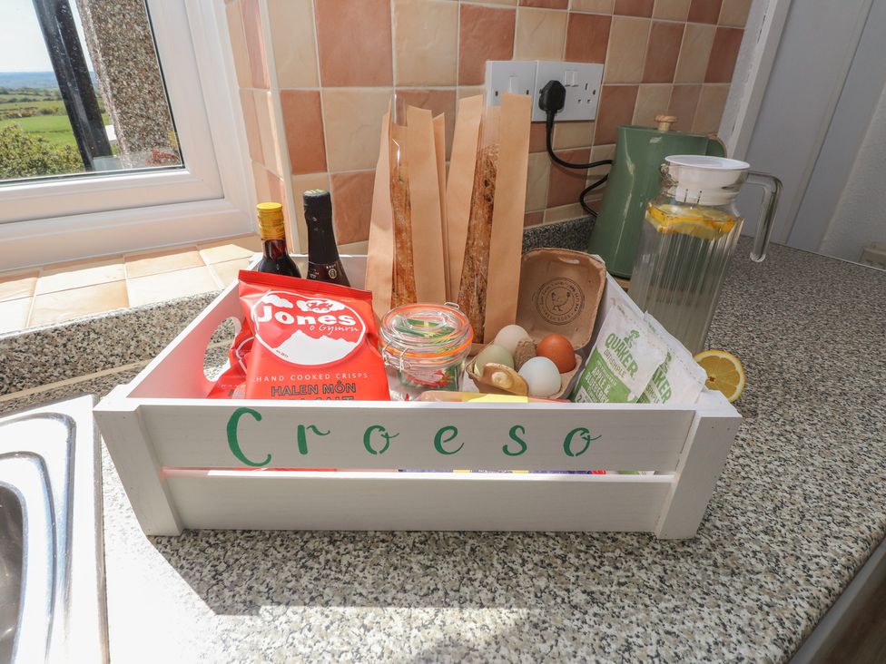 A kitchen with a basket containing food items and drinks at Mona View in Amlwch