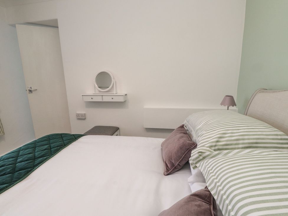 A bedroom with a bed and mirror at Mona View in Amlwch
