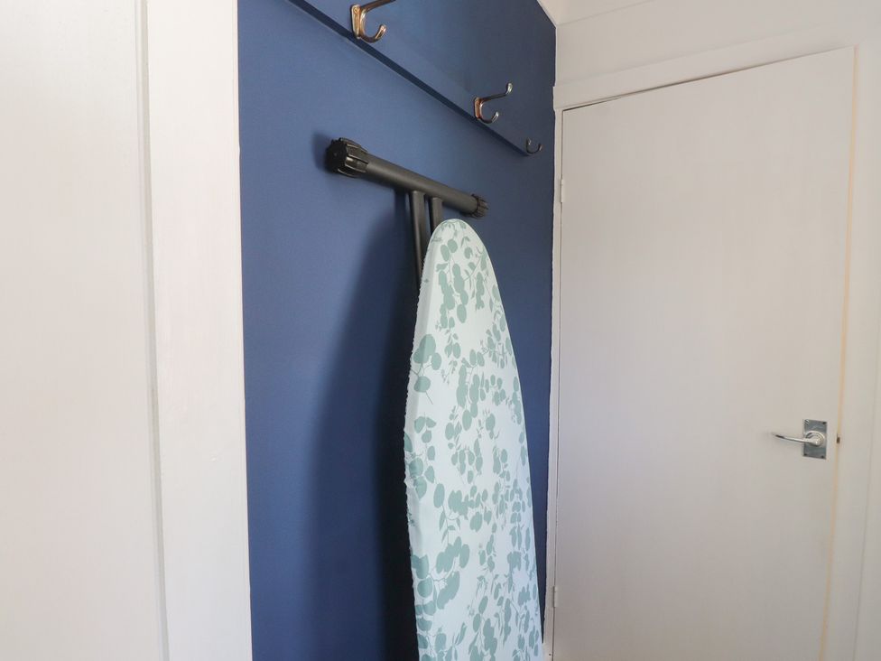 An ironing board and hooks in a laundry room at Mona View in Amlwch
