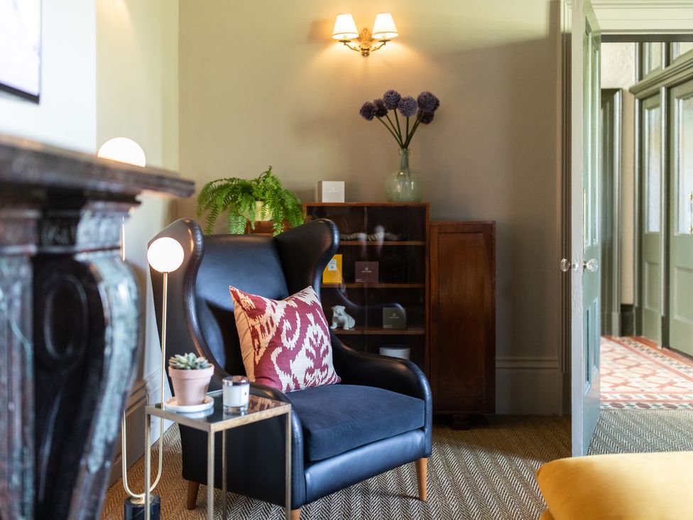 A living room with an armchair and side table at The Country House Cumbria Castle Carrock