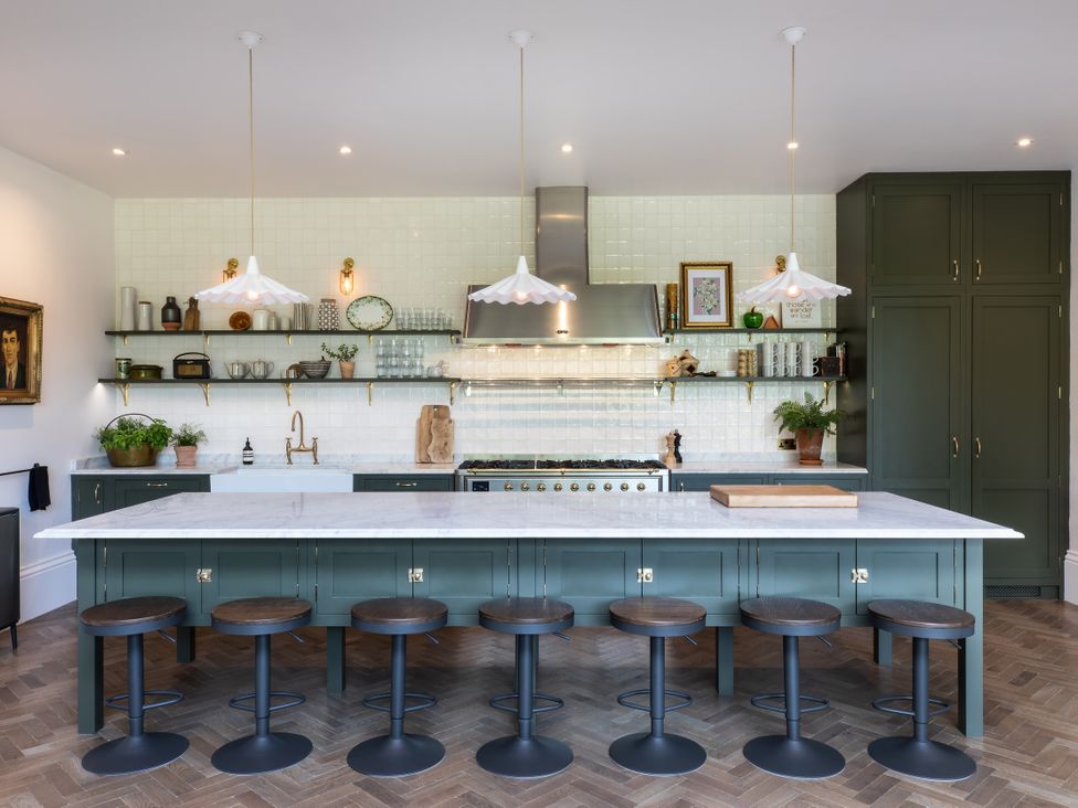 A kitchen with a large island and bar stools at The Country House Cumbria in Castle Carrock