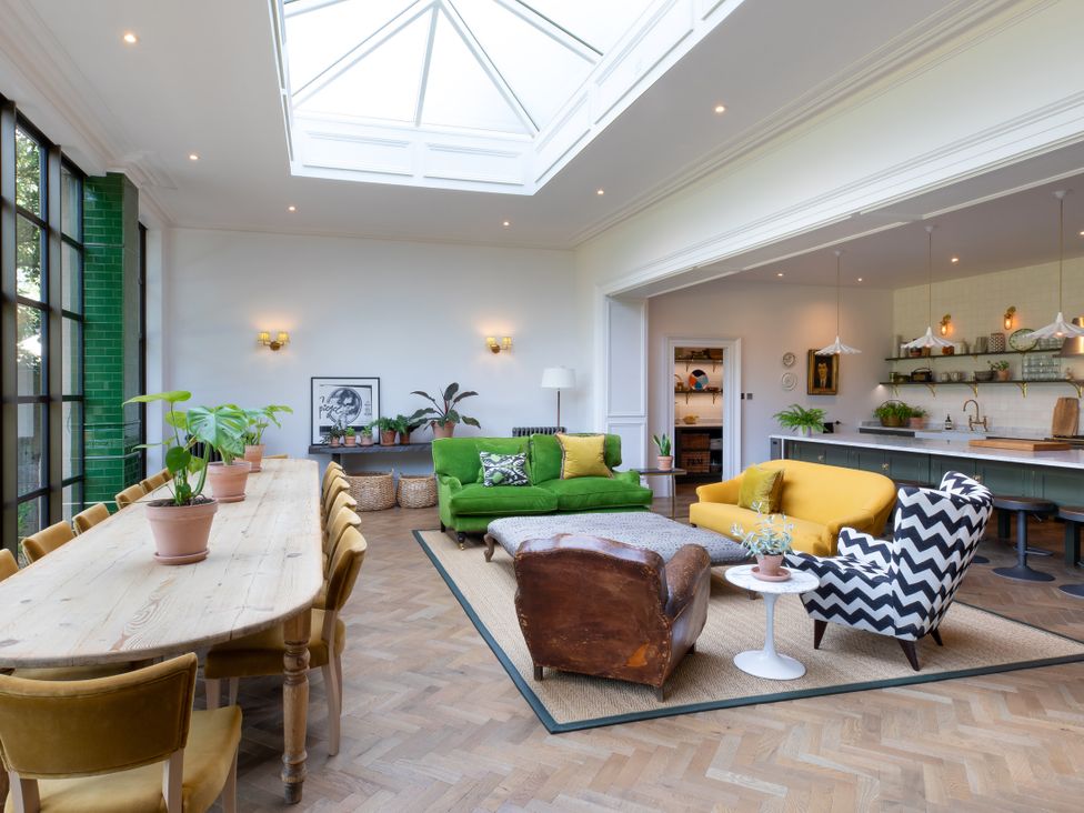 A living room with a green sofa and dining table at The Country House Cumbria Castle Carrock