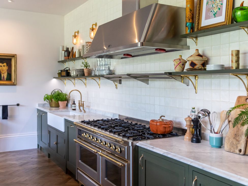 A kitchen with a stove, sink, and shelves at The Country House Cumbria Castle Carrock