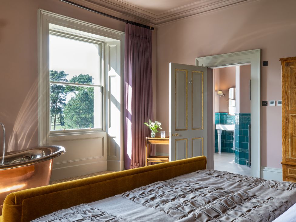 A bedroom with a bed and door leading to a bathroom at The Country House Cumbria Castle Carrock