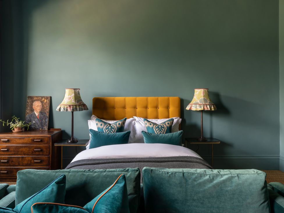 A bedroom with a yellow headboard and bedside lamps at The Country House Cumbria Castle Carrock