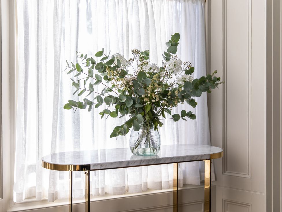 A vase with flowers on a table by the window at The Country House Cumbria Castle Carrock