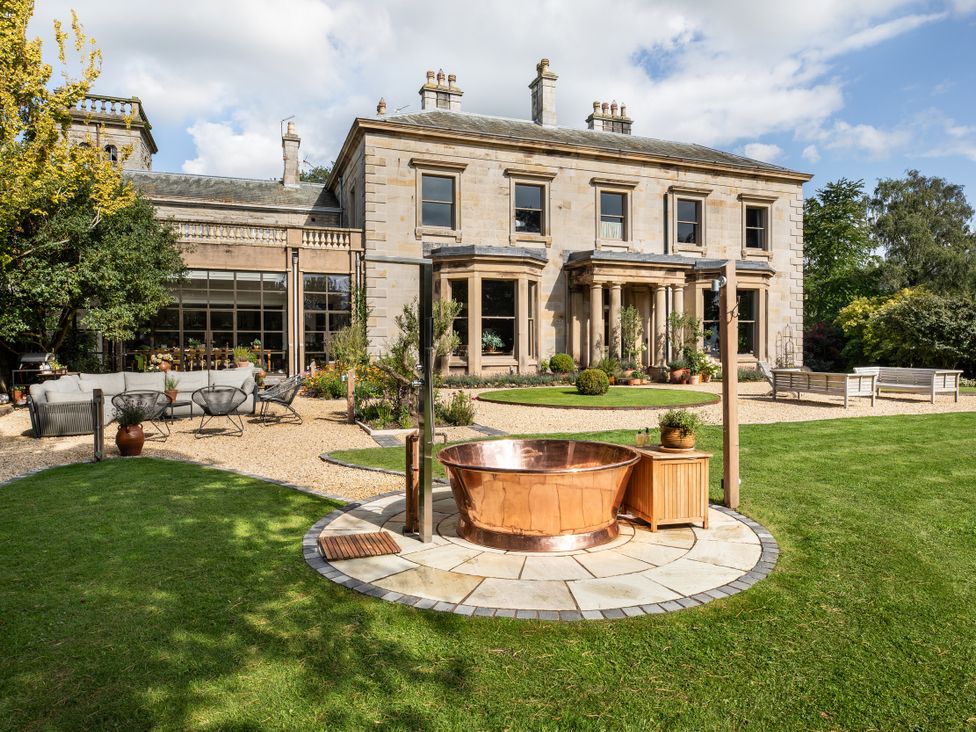 A garden with a copper bathtub and outdoor seating at The Country House Cumbria Castle Carrock