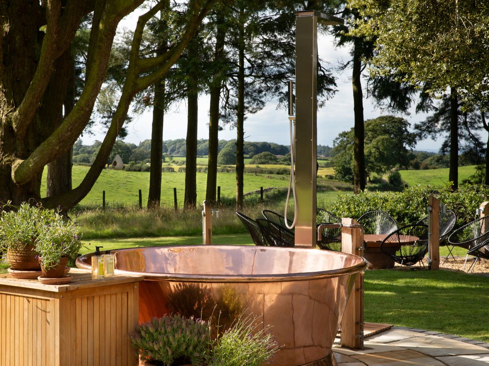 A garden with a hot tub and outdoor shower at The Country House Cumbria Castle Carrock