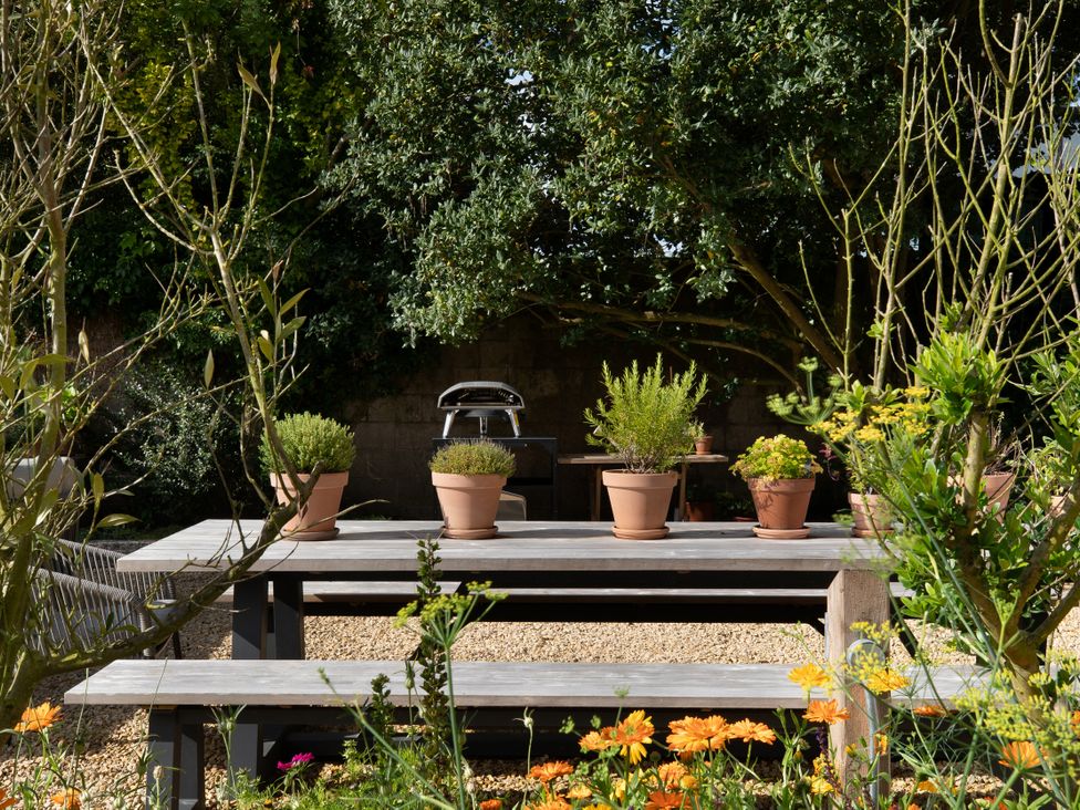 A garden with a table and flower pots at The Country House Cumbria, Castle Carrock