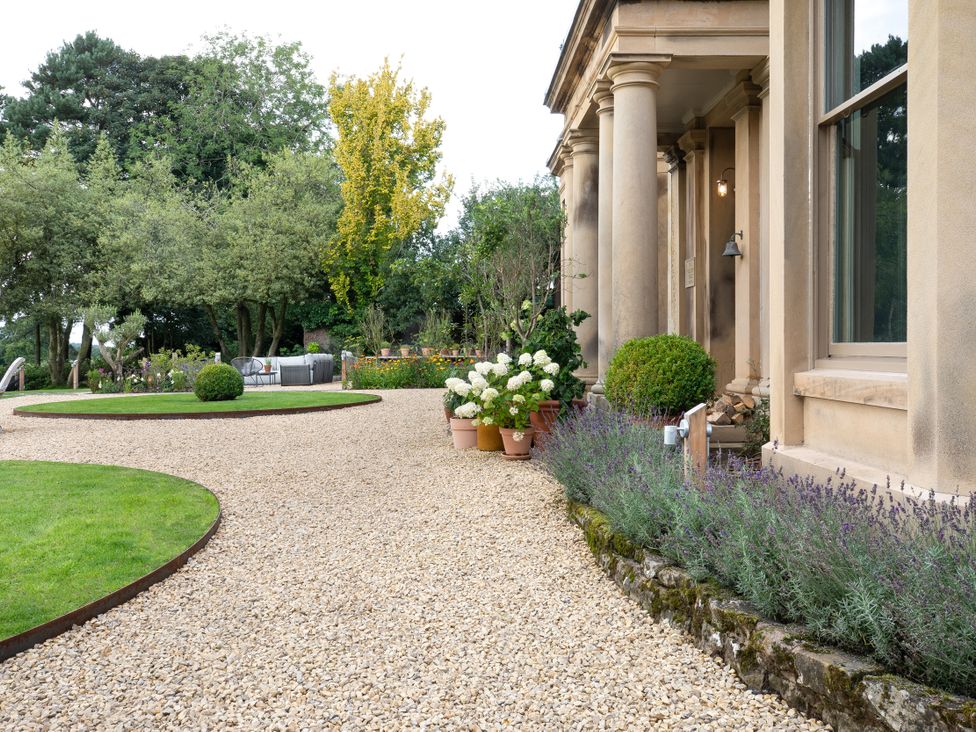 A garden with gravel pathway and flower pots at The Country House Cumbria, Castle Carrock
