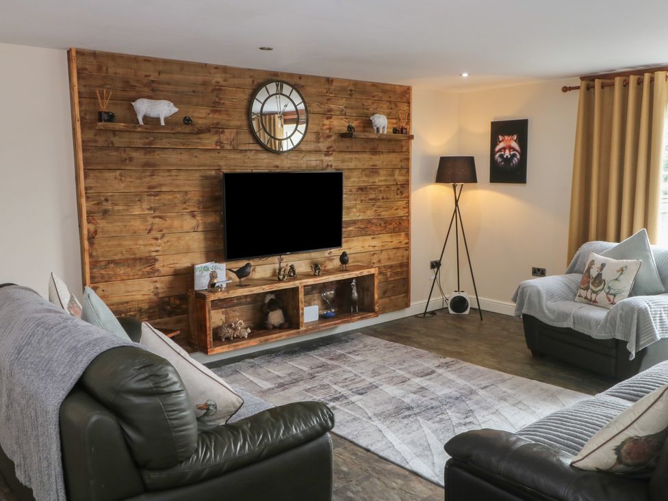 A living room with a television and sofa at Pompian Lodge in Leyland