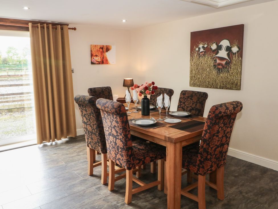 A dining room with a wooden table and floral chairs at Pompian Lodge Leyland