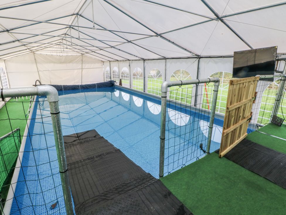 An indoor pool area with a fence and a door at Pompian Lodge Bretherton near Tarleton