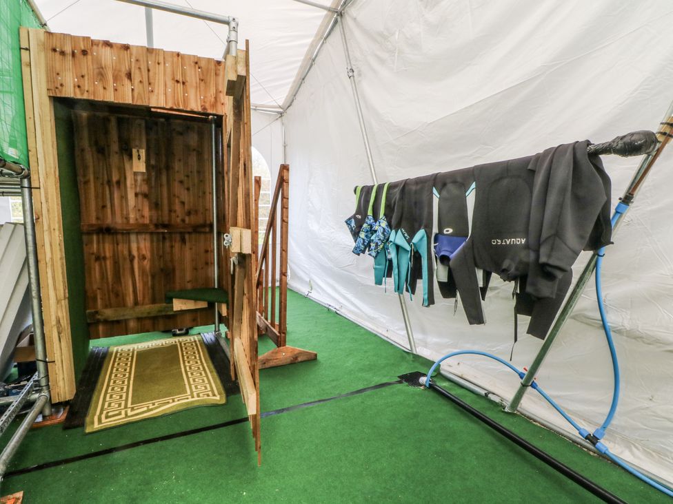 An outdoor changing area with a shower and wetsuits hanging at Pompian Lodge Bretherton near Tarleton
