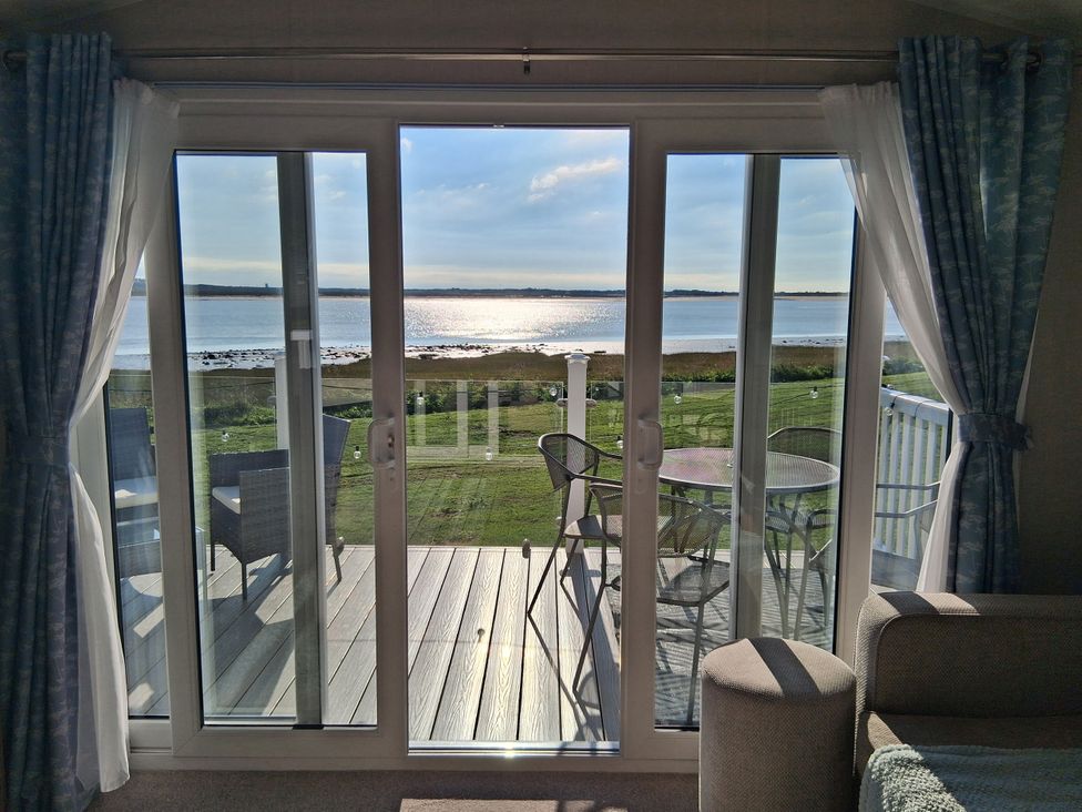 A living room with sliding doors leading to a deck at Willerby Malton 2023 in Kidwelly