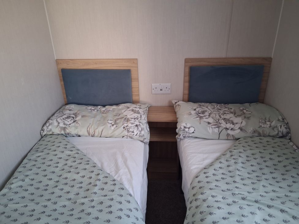 A bedroom with two single beds and a bedside table at Willerby Malton 2023 in Kidwelly