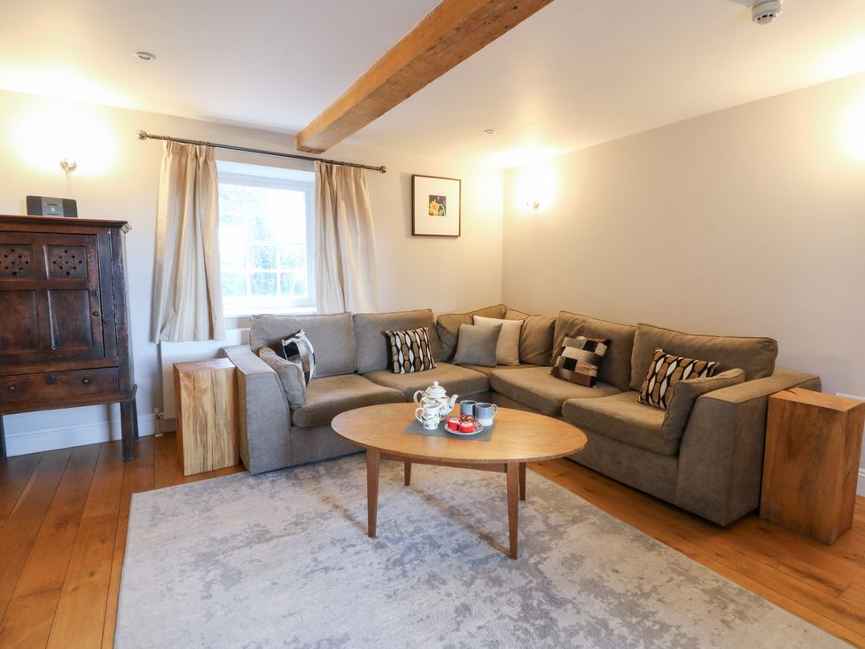 A living room with a sofa, coffee table and wooden cabinet at Secret Garden Cottage Ciliau Aeron near Aberaeron