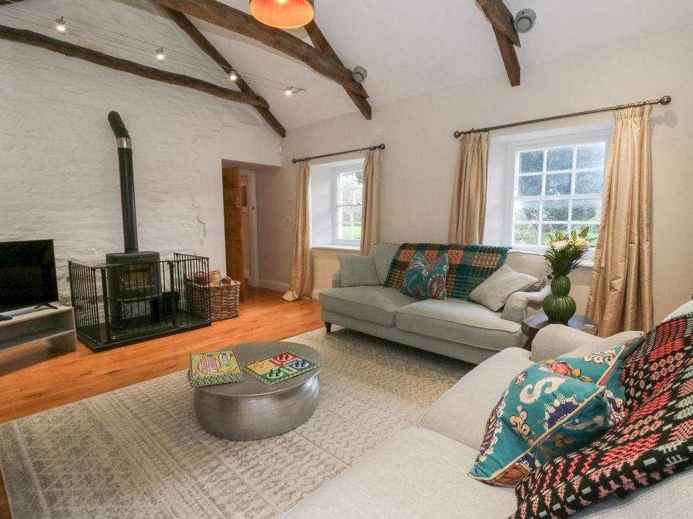 A living room with a sofa, coffee table and stove at Secret Garden Cottage in Ciliau Aeron near Aberaeron