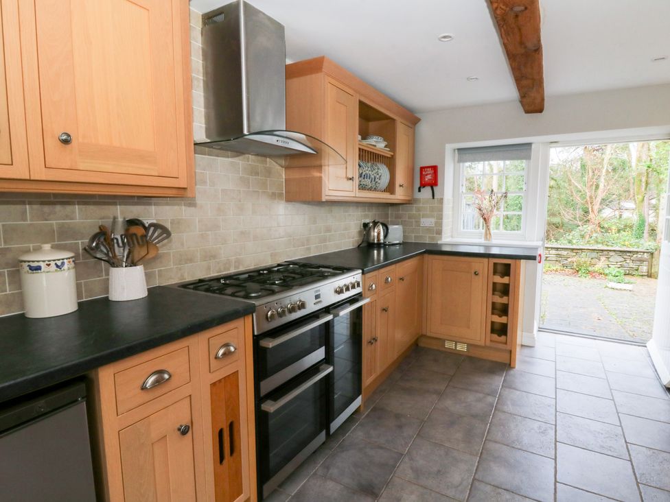 A kitchen with wooden cabinets and an oven at Secret Garden Cottage in Ciliau Aeron near Aberaeron