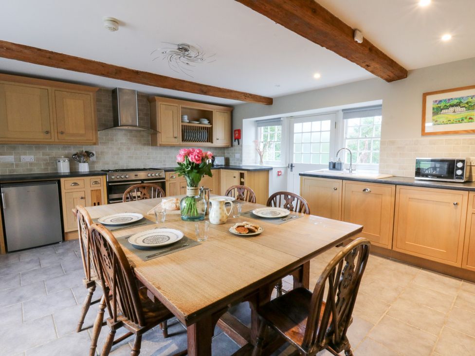 A kitchen with a wooden table and chairs at Secret Garden Cottage in Ciliau Aeron near Aberaeron