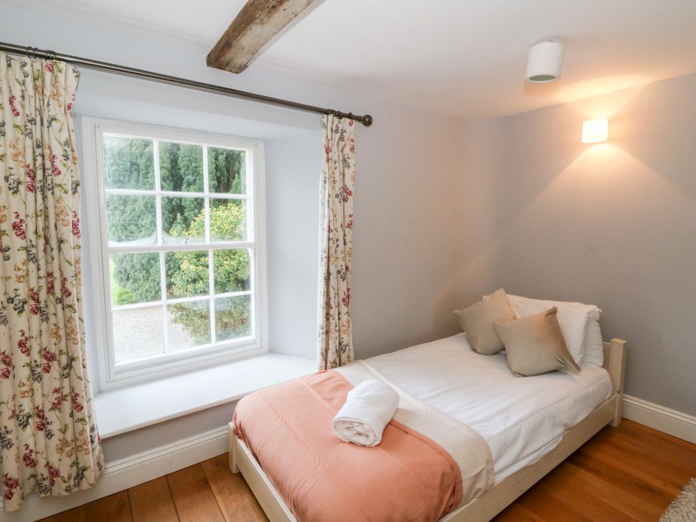 A bedroom with a bed and window at Secret Garden Cottage in Ciliau Aeron near Aberaeron