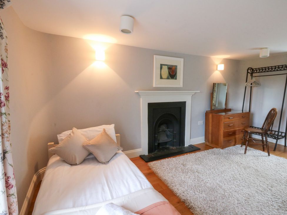 A bedroom with a bed and fireplace at Secret Garden Cottage in Ciliau Aeron near Aberaeron