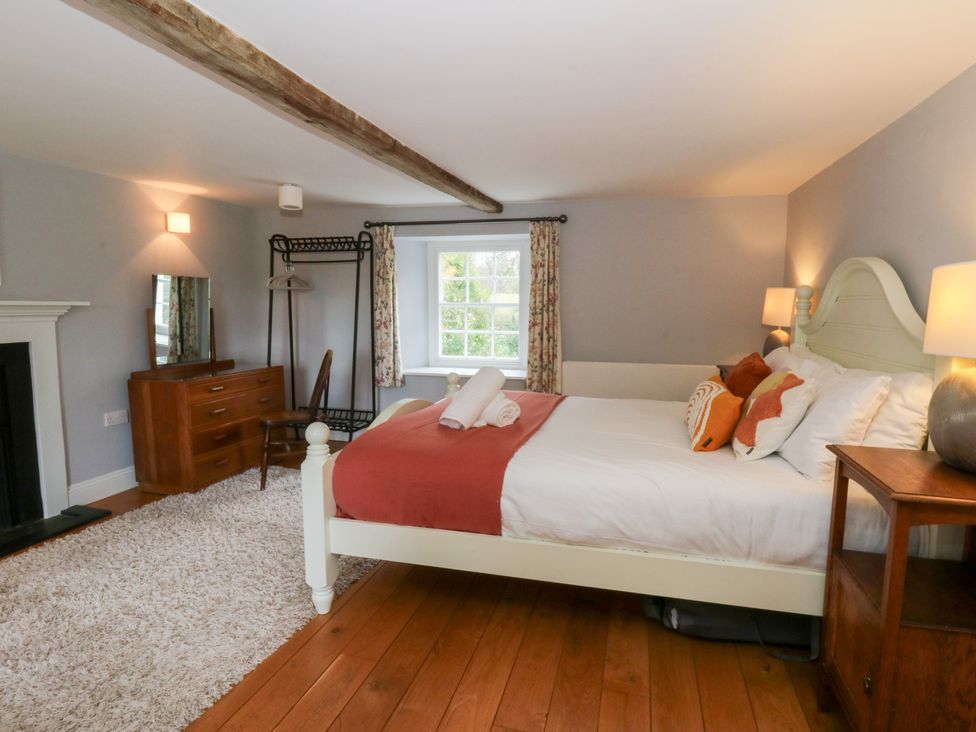 A bedroom with a bed and dressing table at Secret Garden Cottage Ciliau Aeron near Aberaeron