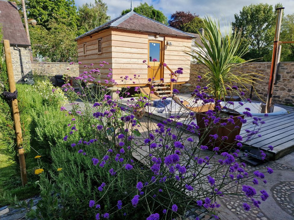 A garden with flowers and a wooden structure at Secret Garden Cottage Ciliau Aeron near Aberaeron