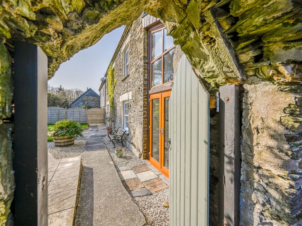 An outdoor pathway with a stone wall and door at The Old Farm House near Pelynt
