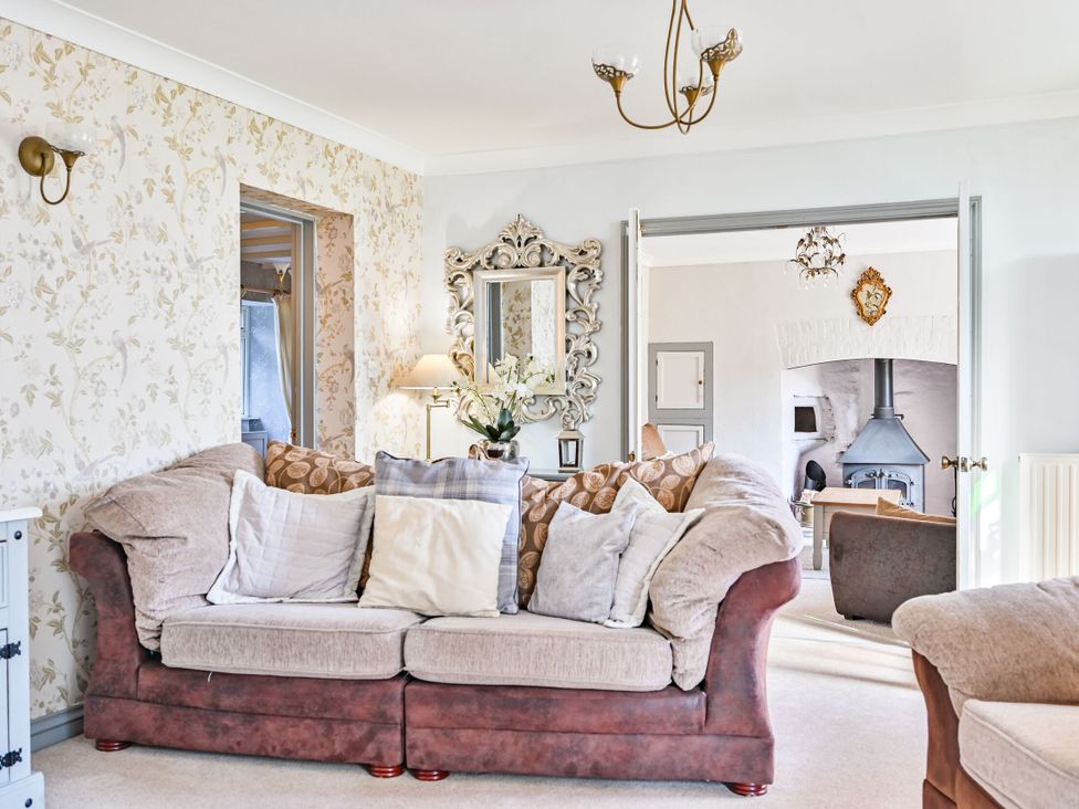 A living room with a sofa and a mirror at The Old Farm House near Pelynt