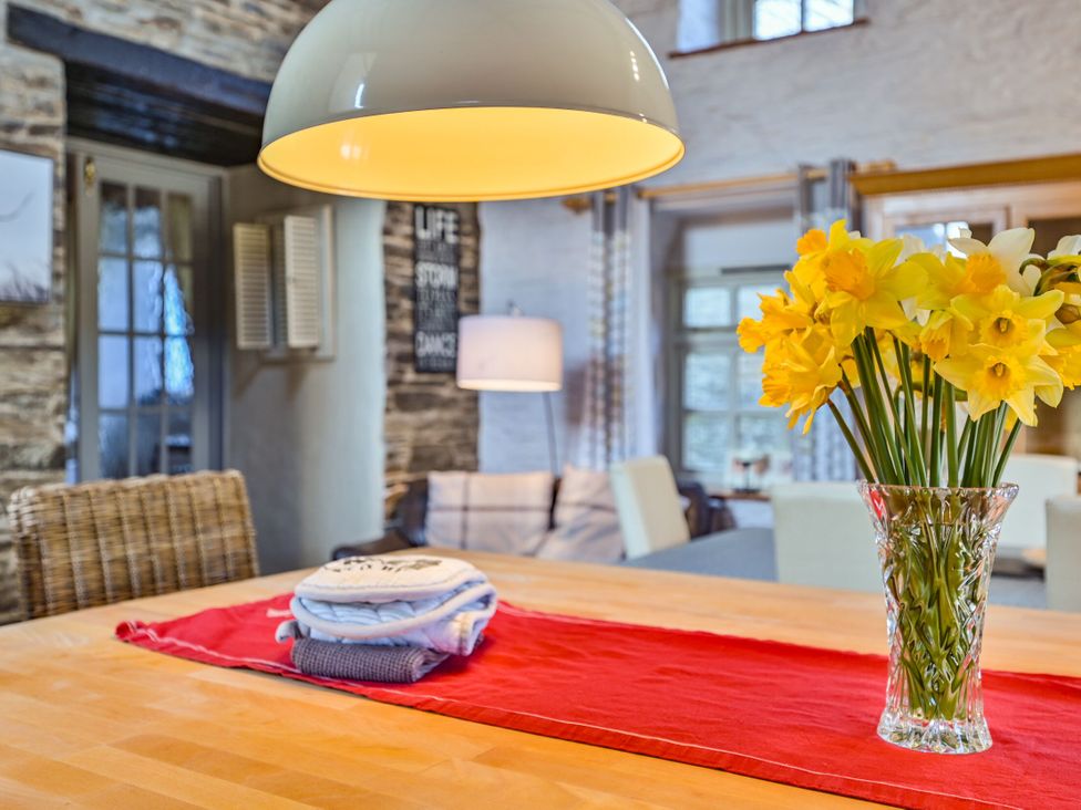 A dining room table with a vase of flowers at The Old Farm House near Pelynt