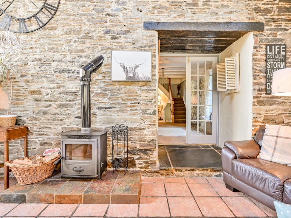A living room with a stove and wooden table at The Old Farm House near Pelynt