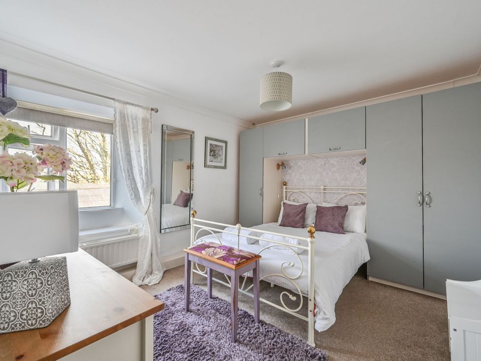 A bedroom with a bed, wardrobe, and table at The Old Farm House near Pelynt