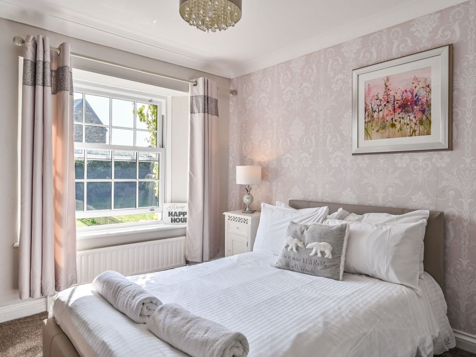 A bedroom with a bed, lamp, and window at The Old Farm House near Pelynt