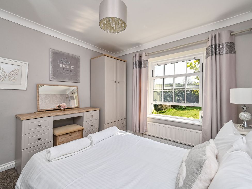 A bedroom with a bed and dressing table at The Old Farm House near Pelynt