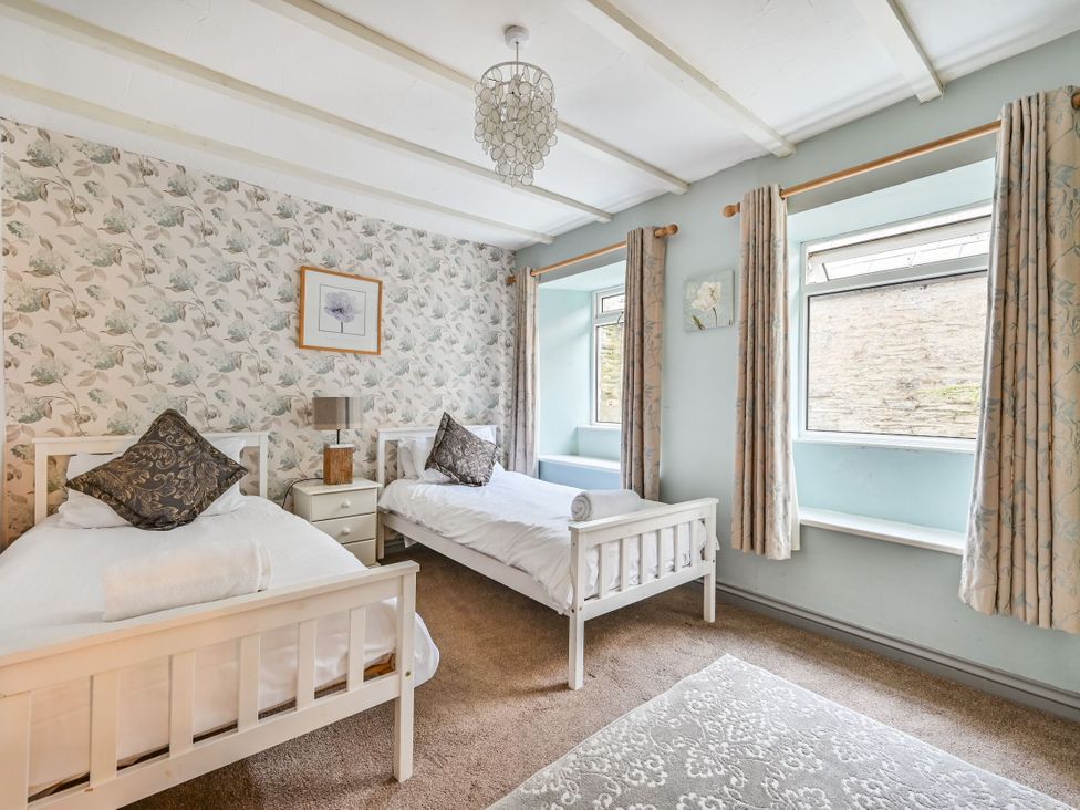 A bedroom with two single beds and a window at The Old Farm House near Pelynt