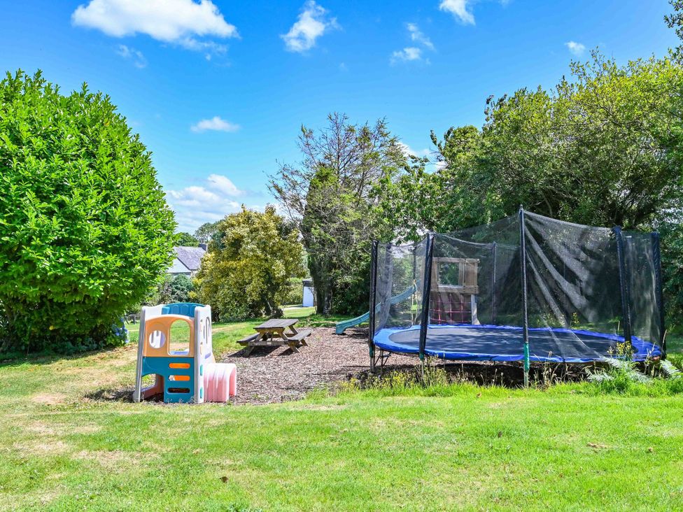 A garden with a trampoline and playhouse at The Old Farm House near Pelynt