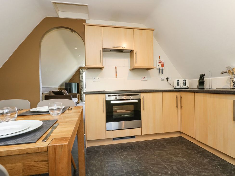 A kitchen with cabinets, oven, and dining table at Valley Lodge 61 Callington