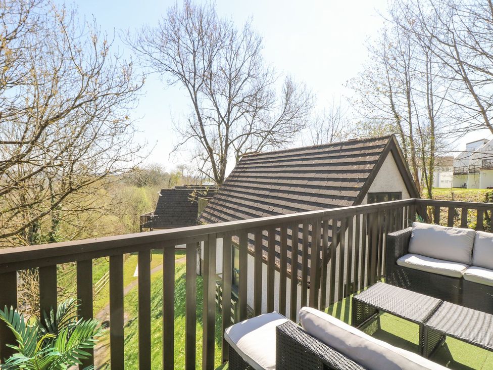 A balcony with seating and view of trees and buildings at Valley Lodge 61 in Callington